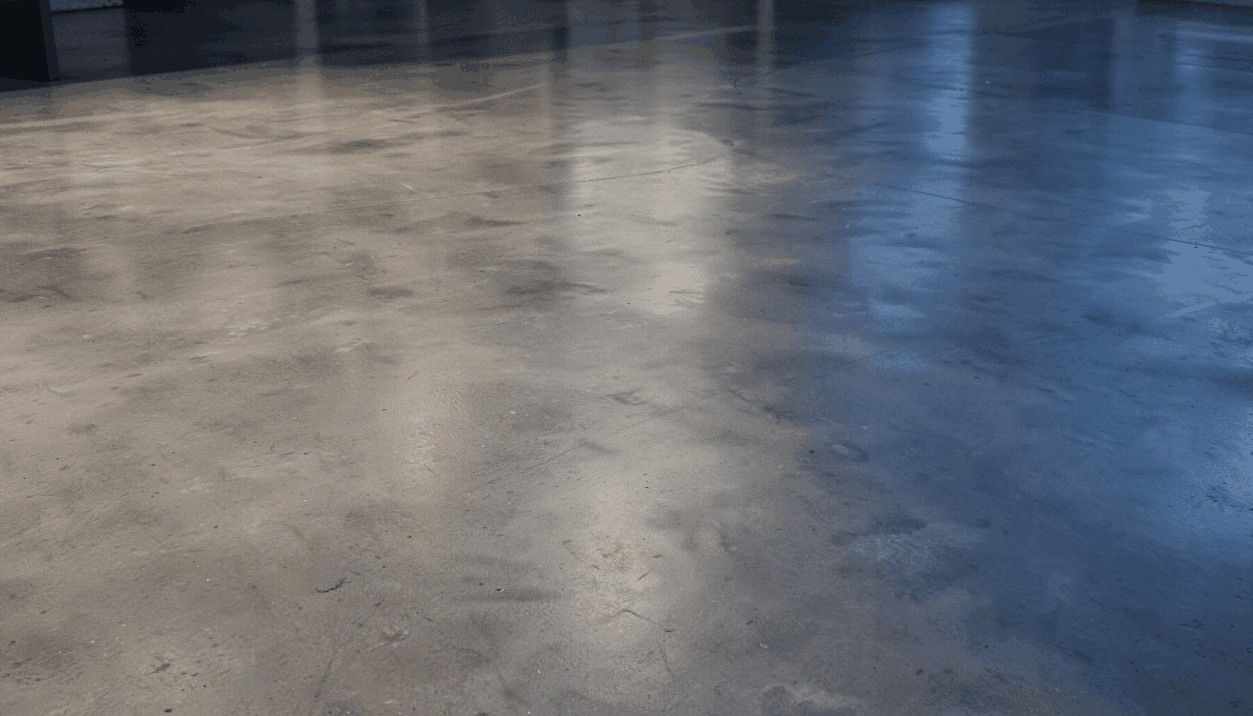 Wide view of a polished concrete floor with a subtle sheen, warm gray tones, and a clean industrial aesthetic