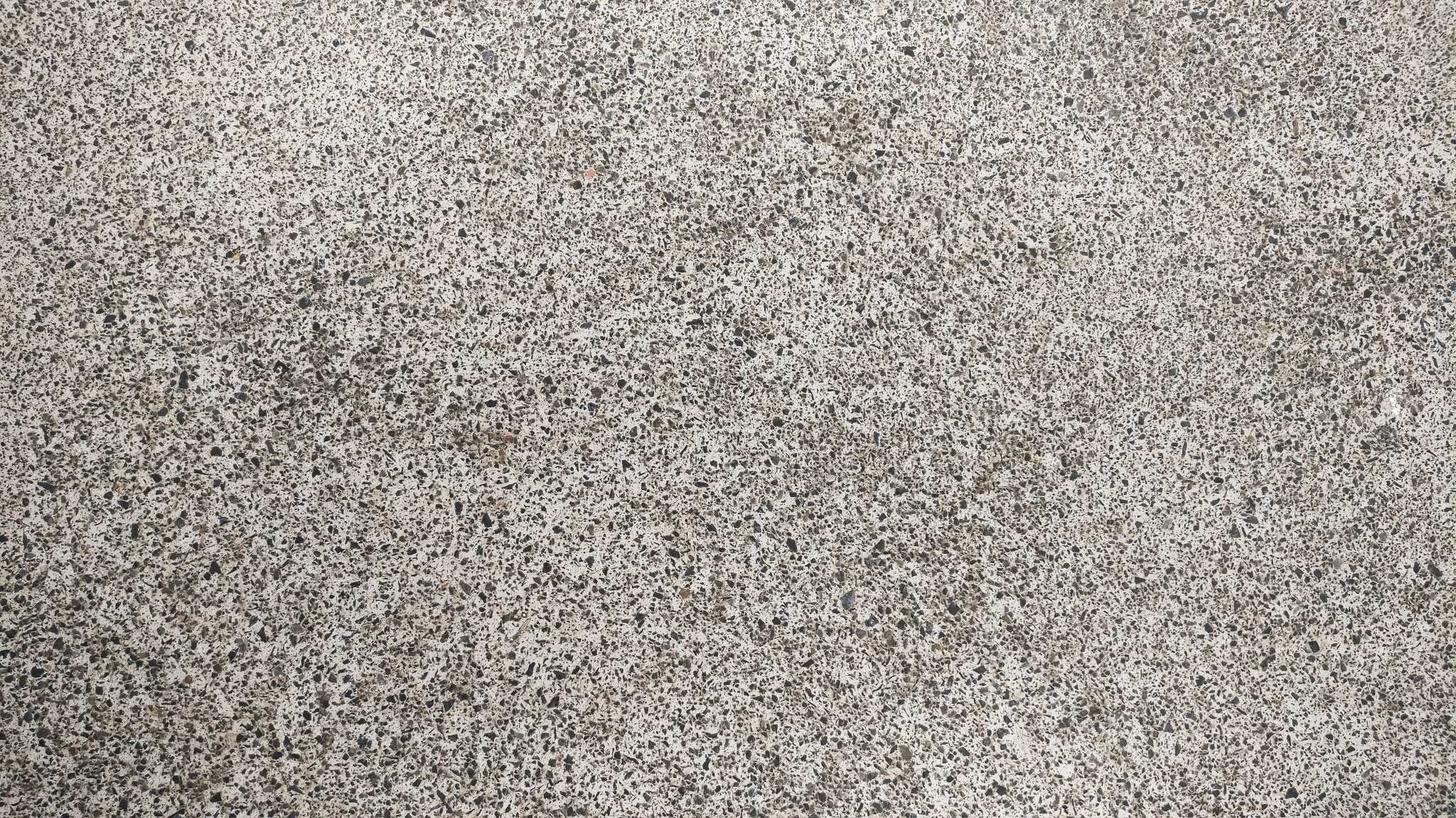 Speckled gray and beige stone-textured surface with subtle terrazzo-like flecks, conveying a clean industrial finish
